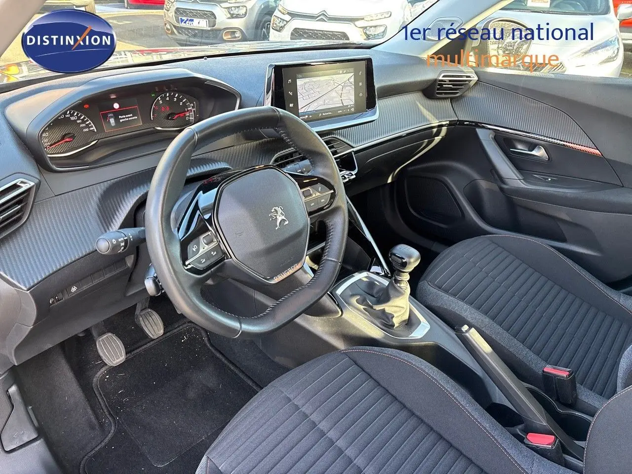 Intérieur avant du Peugeot 2008 gris Artense 2021, vue sur le volant, tableau de bord et levier de vitesse manuel.