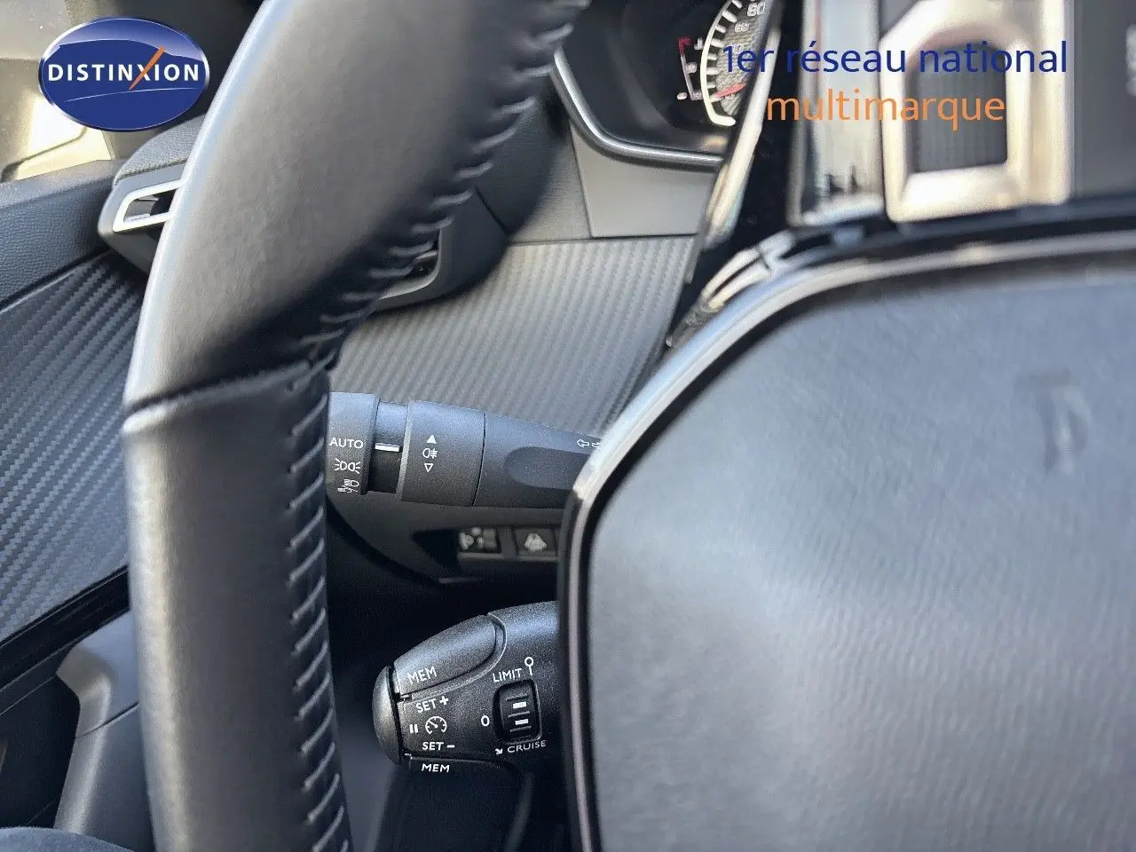 Gros plan sur le volant et les commandes de régulateur de vitesse d'une Peugeot 2008 gris Artense, intérieur noir.