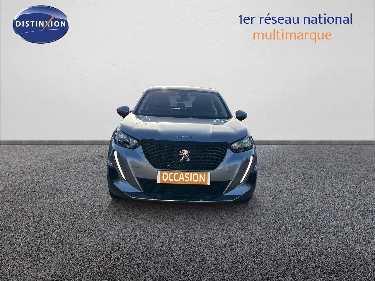 Vue frontale d'un Peugeot 2008 gris Artense avec calandre noire et feux LED, sur fond neutre avec panneau Distinxion.