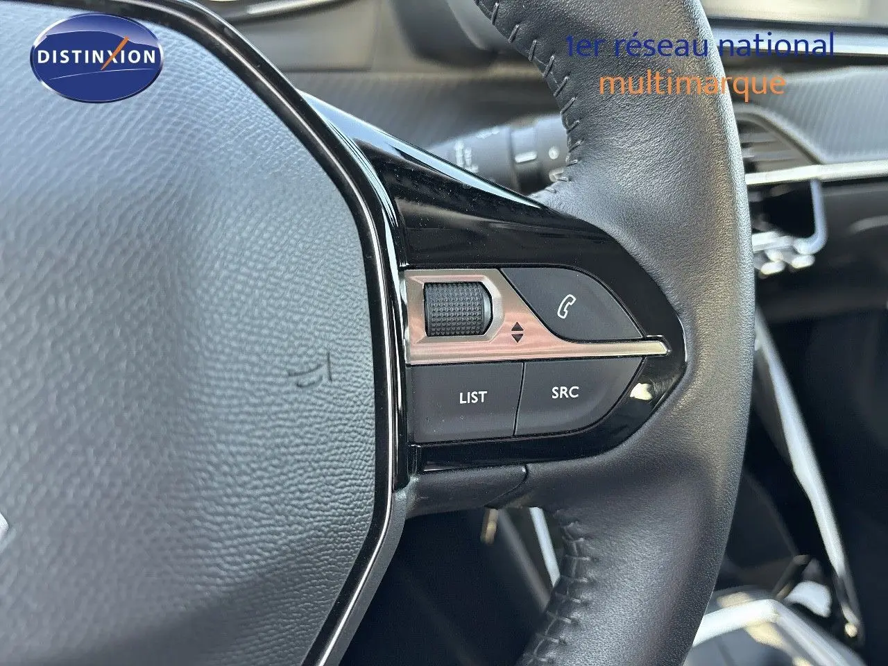 Gros plan sur les commandes au volant en cuir noir du Peugeot 2008 gris Artense, version 1.2 PureTech 130 Active de 2021.