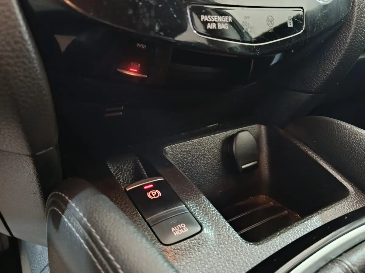 Gros plan sur la console centrale noire du Nissan Qashqai 2019, montrant frein à main électrique et prise 12V.