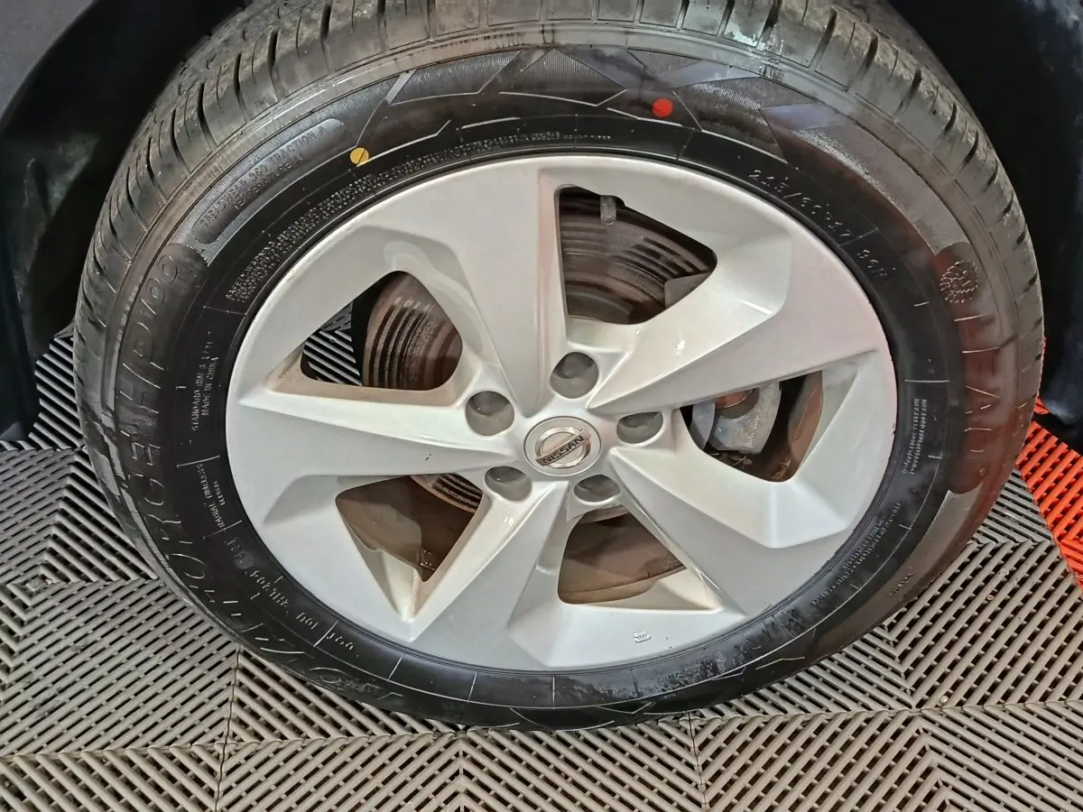 Gros plan sur la roue avant droite avec jante argentée du Nissan Qashqai gris clair 2019.