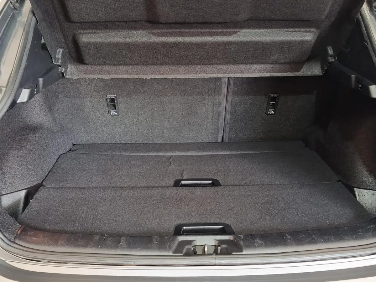 Coffre ouvert du Nissan Qashqai gris clair, vue de l'arrière montrant la surface de chargement et la tablette de séparation.