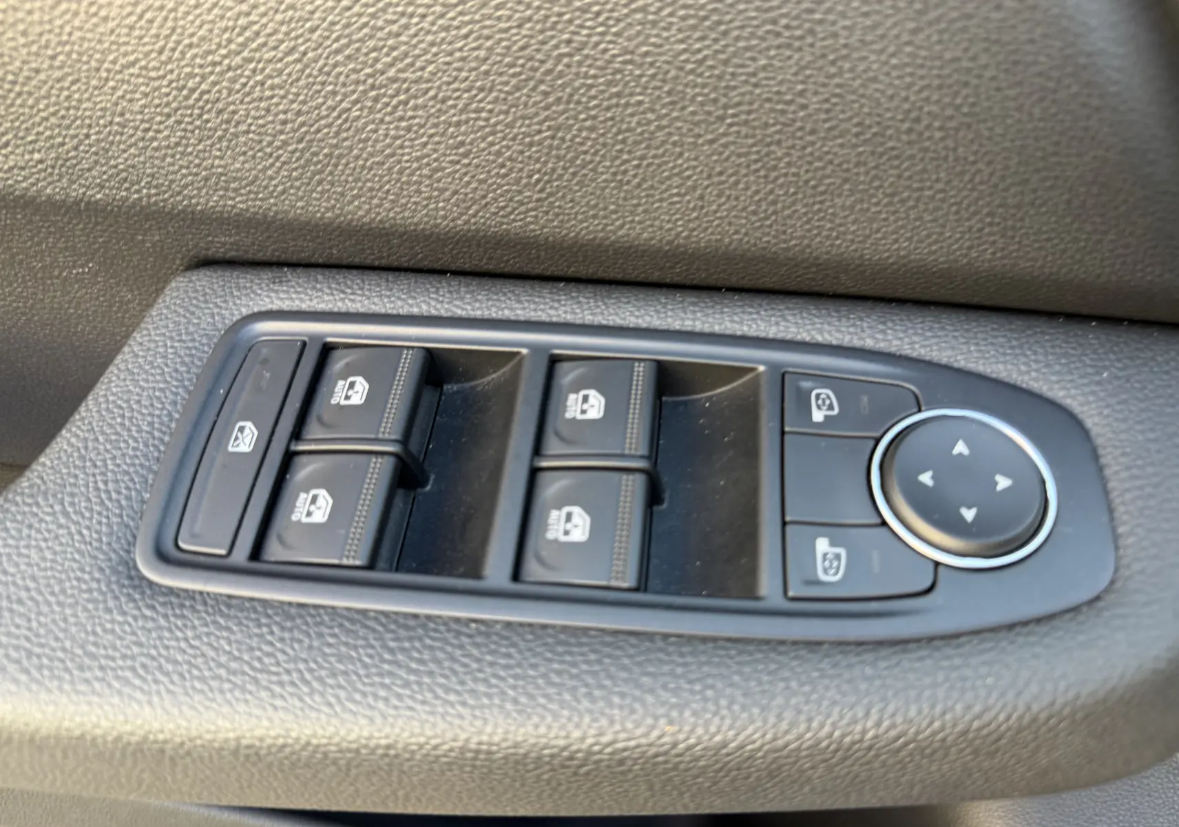 Panneau de commandes des vitres et rétroviseurs côté conducteur dans une Renault Clio V, finition tissu noir.