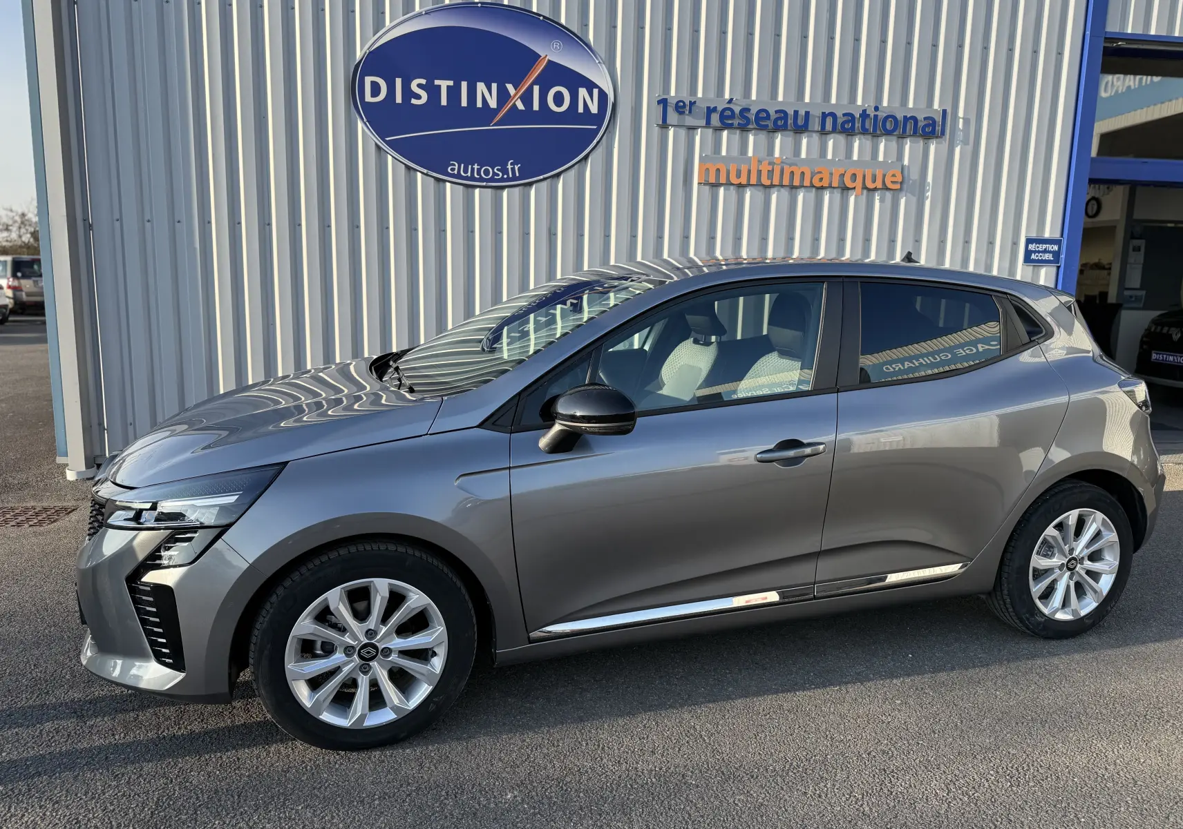 Renault Clio V gris schiste métal vue de profil côté gauche, avec jantes alliage et poignées de porte noires.