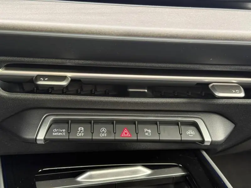 Vue rapprochée du tableau de bord de l'Audi Q3 2026 noir métallisé, montrant la rangée de boutons de commande.