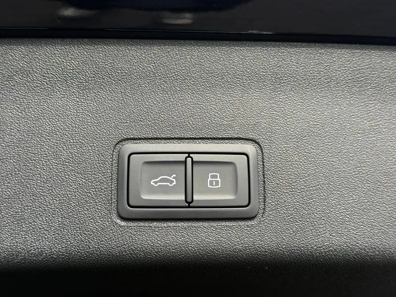 Boutons de commande pour ouverture du coffre et verrouillage, intégrés dans un panneau intérieur noir texturé.