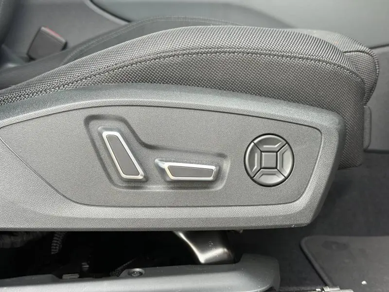 Gros plan sur les commandes de réglage électrique du siège conducteur d'un Audi Q3 noir Mythique métallisé.