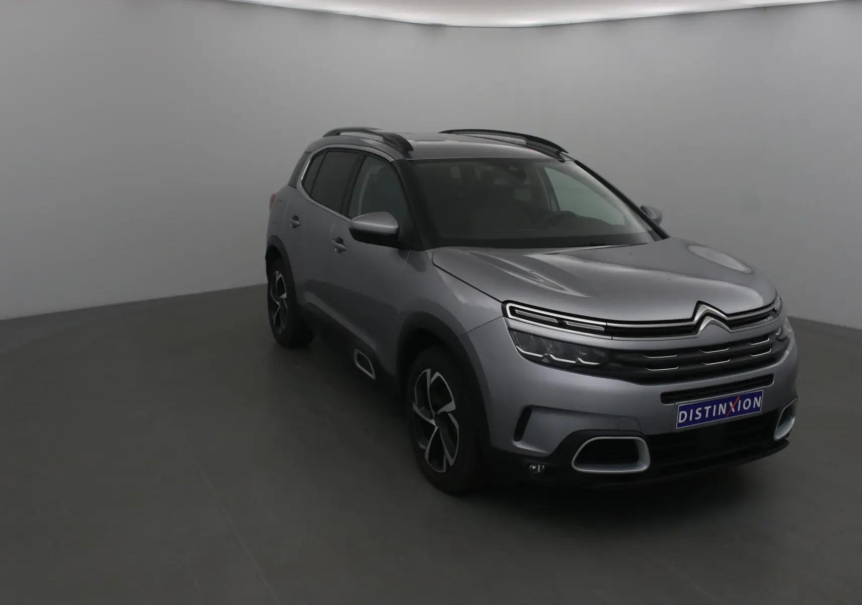 Citroën C5 Aircross gris Artense en 3/4 avant droit, avec toit noir et jantes alliage distinctives.