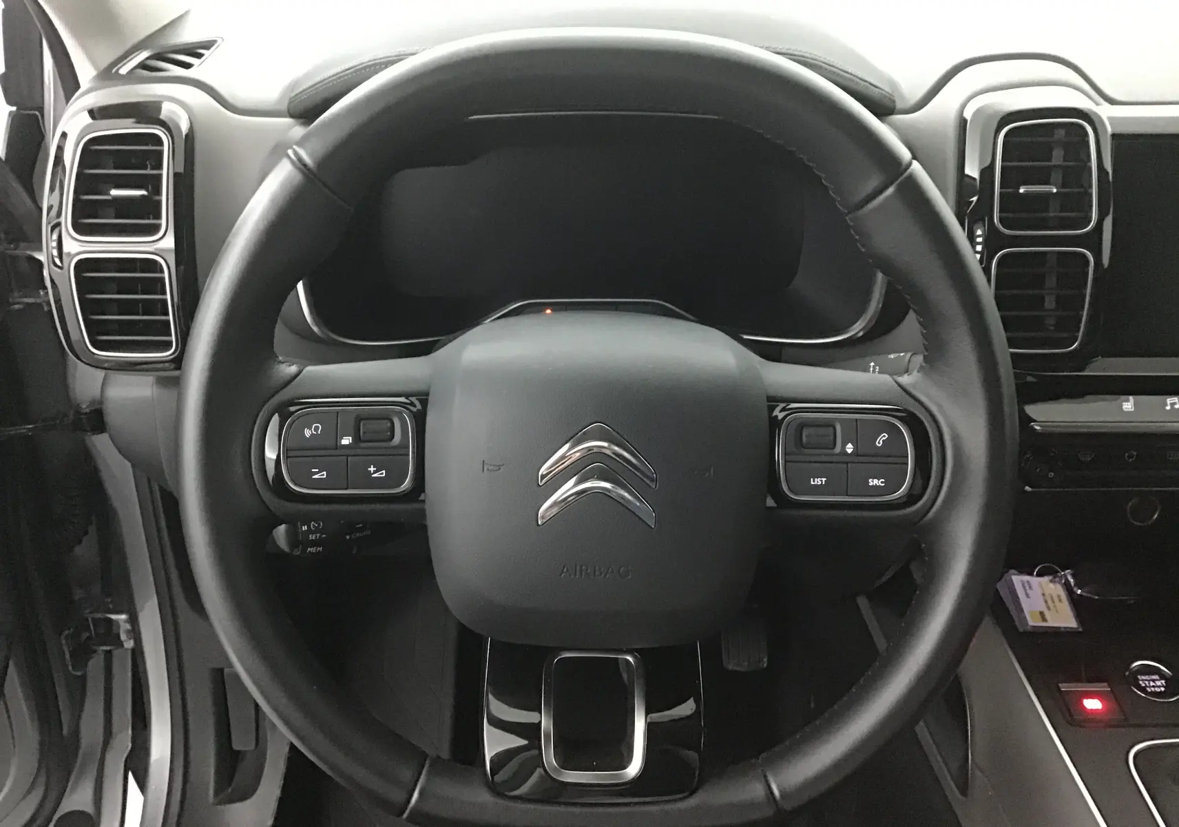 Vue centrée sur le volant en cuir noir du Citroën C5 Aircross gris, avec commandes intégrées et tableau de bord numérique.