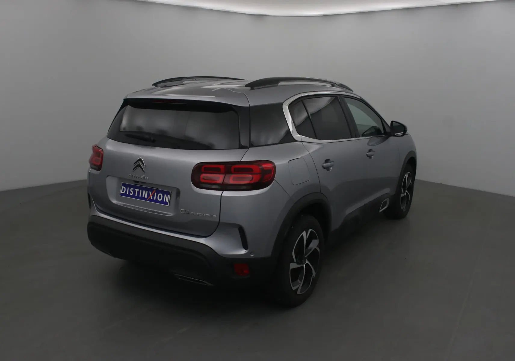 Vue 3/4 arrière droite d'un Citroën C5 Aircross gris Artense avec vitres teintées et jantes noires et argentées.