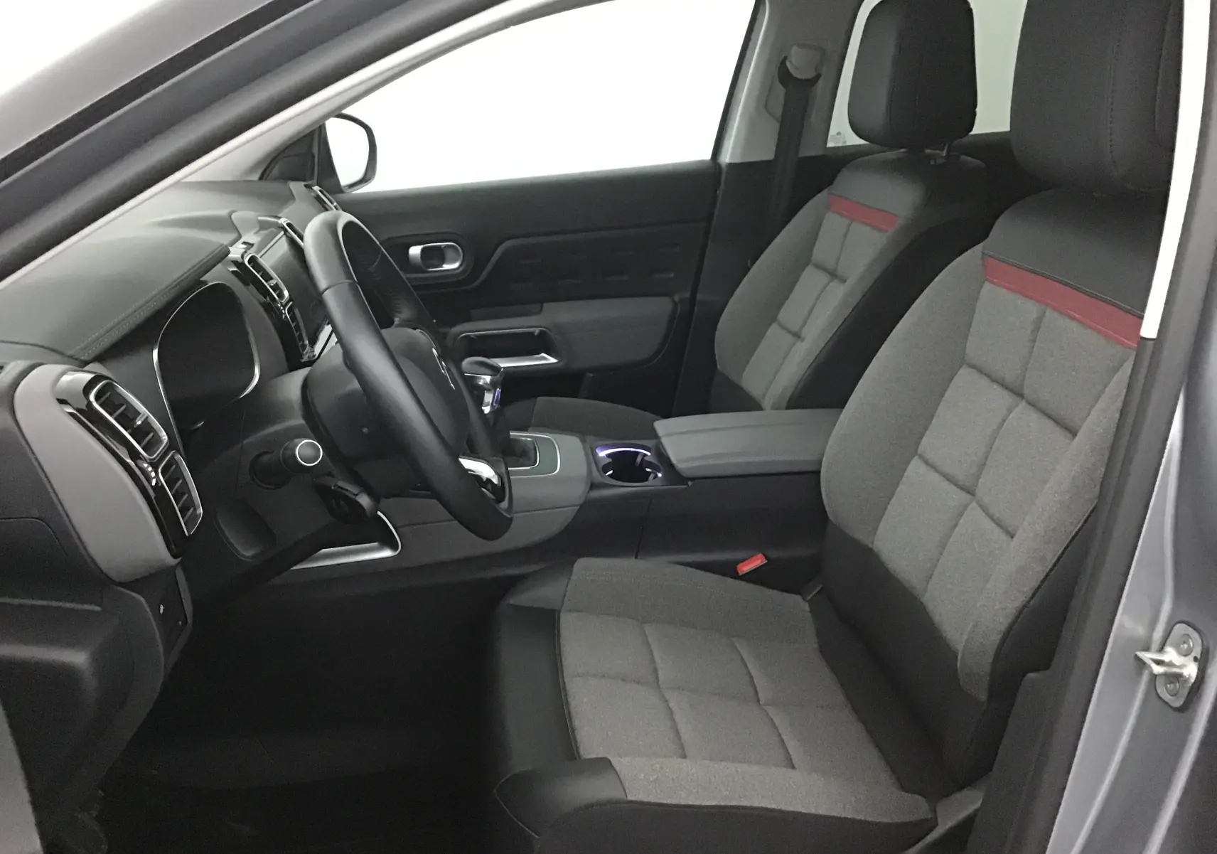 Intérieur avant droit du Citroën C5 Aircross gris Artense 2021, sièges tissu gris avec bande rouge et volant cuir.