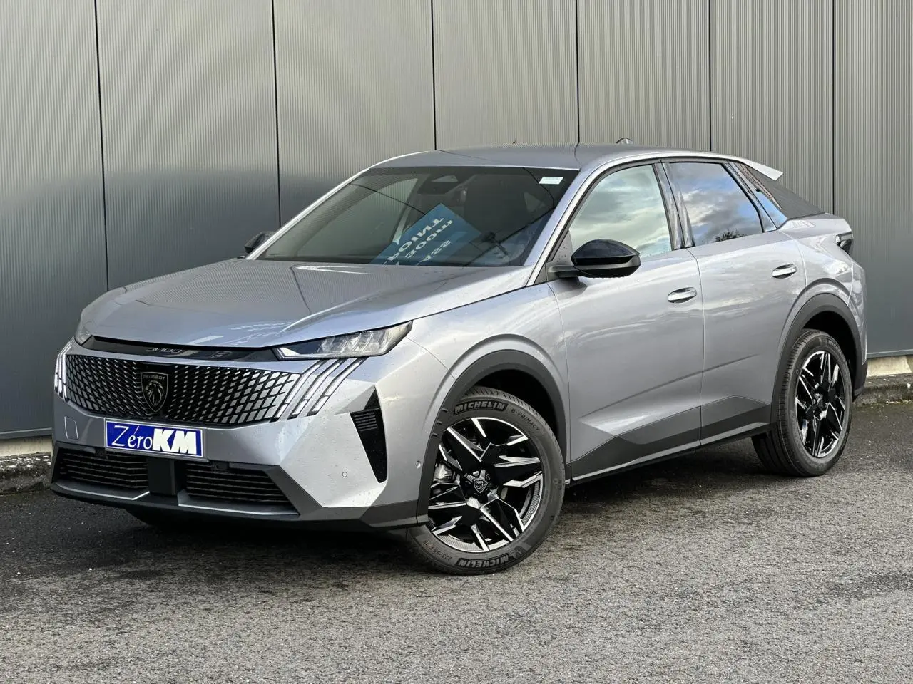 Peugeot 3008 Hybrid gris Artense en 3/4 avant droit, avec jantes alliage noires et calandre distinctive.