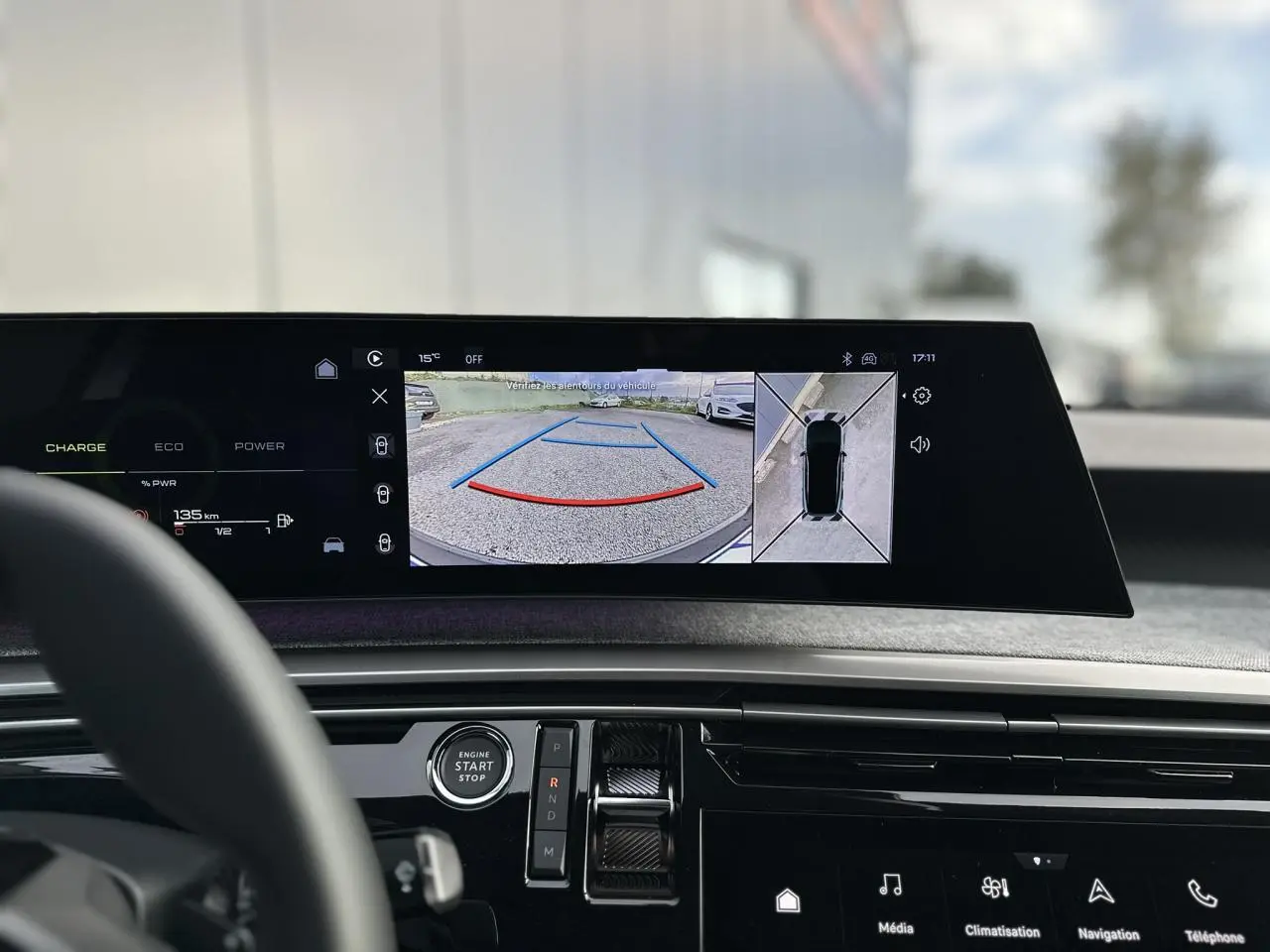 Vue intérieure du tableau de bord du Peugeot 3008 Hybrid gris Artense, écran panoramique affichant caméra 360° et aide au stationnement.