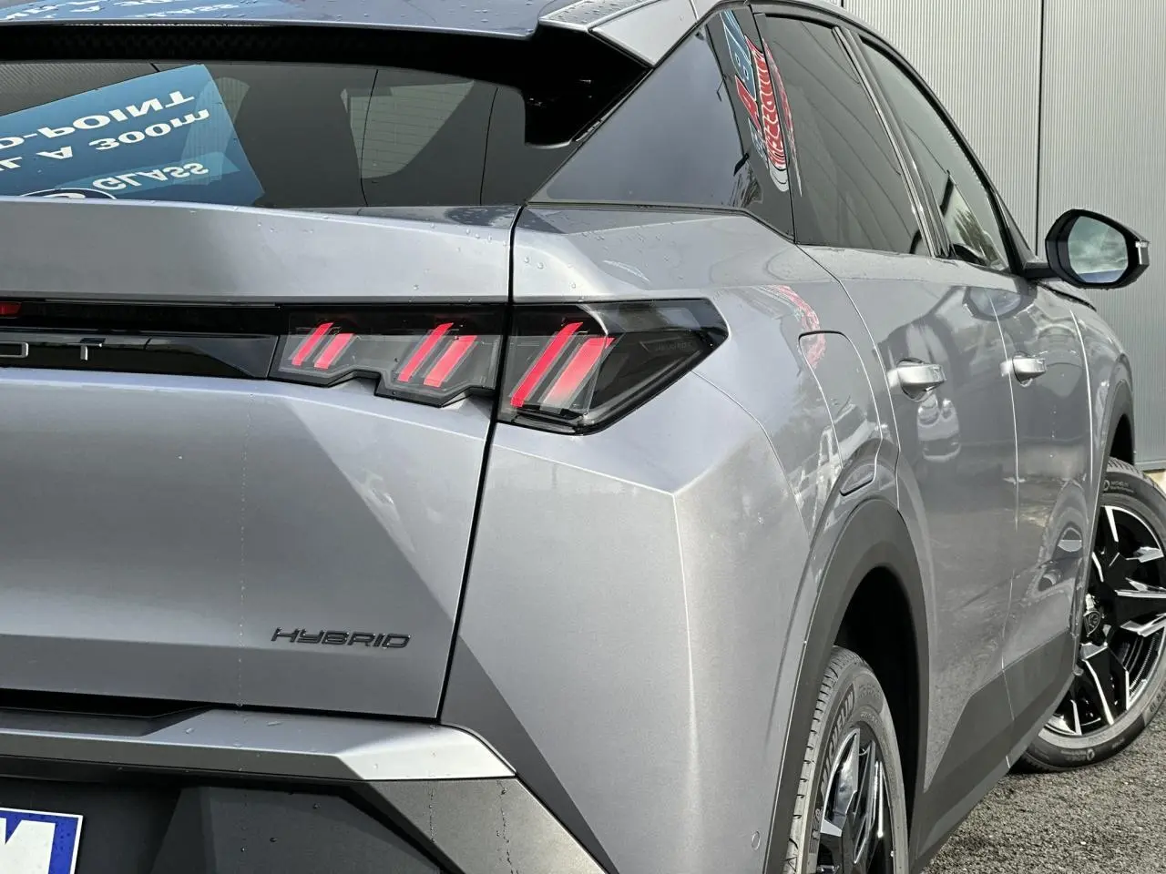 Vue 3/4 arrière droit du Peugeot 3008 Hybrid gris Artense avec feux arrière LED à 3 griffes et jantes alliage noires.