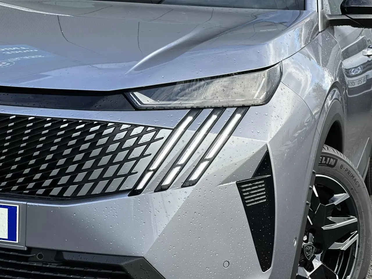 Gros plan sur l'avant droit gris Artense du Peugeot 3008 Hybrid 2025 avec feux LED griffés et jante alliage noire.