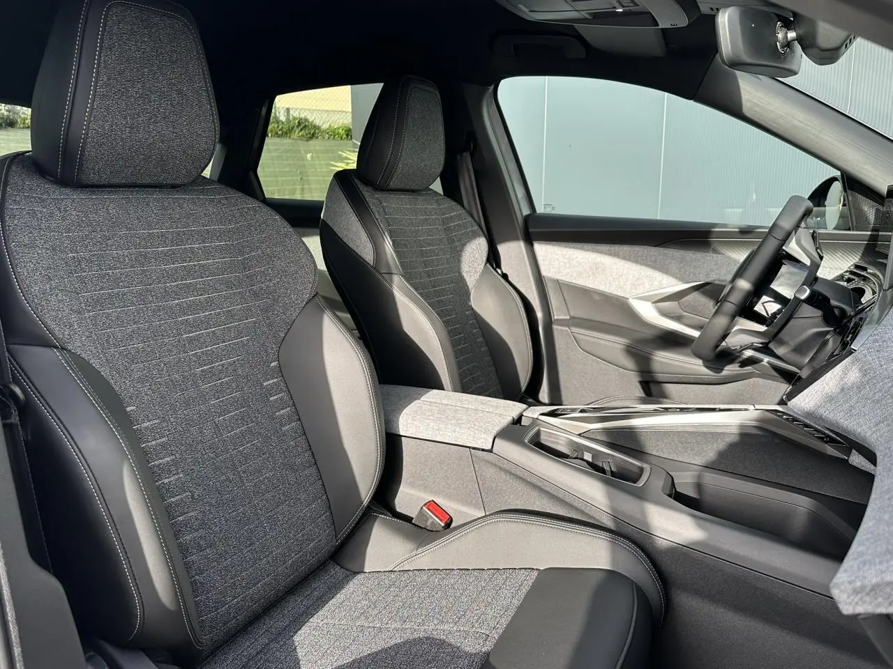 Vue intérieure côté droit des sièges avant gris tissu et cuir du Peugeot 3008 Hybrid 145 Allure avec console centrale moderne.