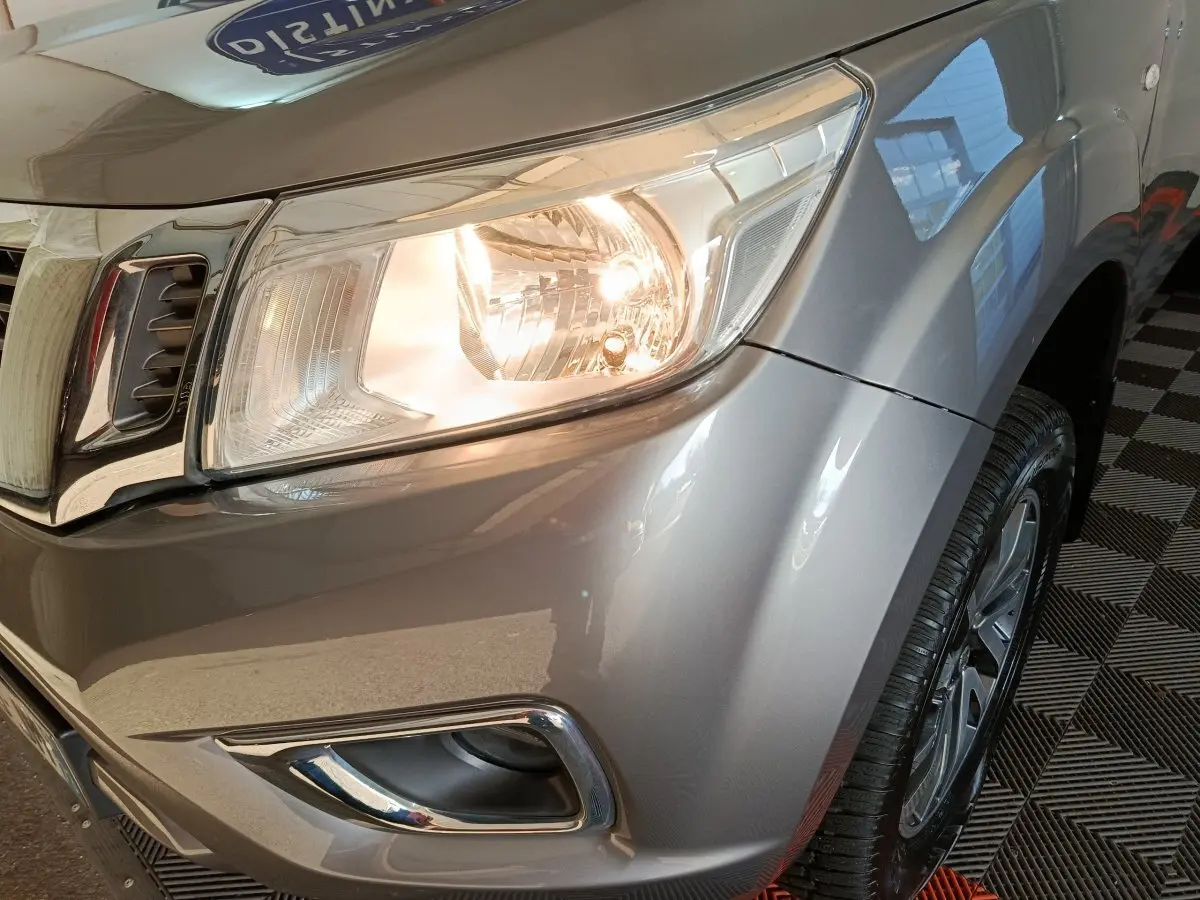 Gros plan sur l'avant droit gris clair du Nissan Navara 2018 avec phare allumé et jante visible.
