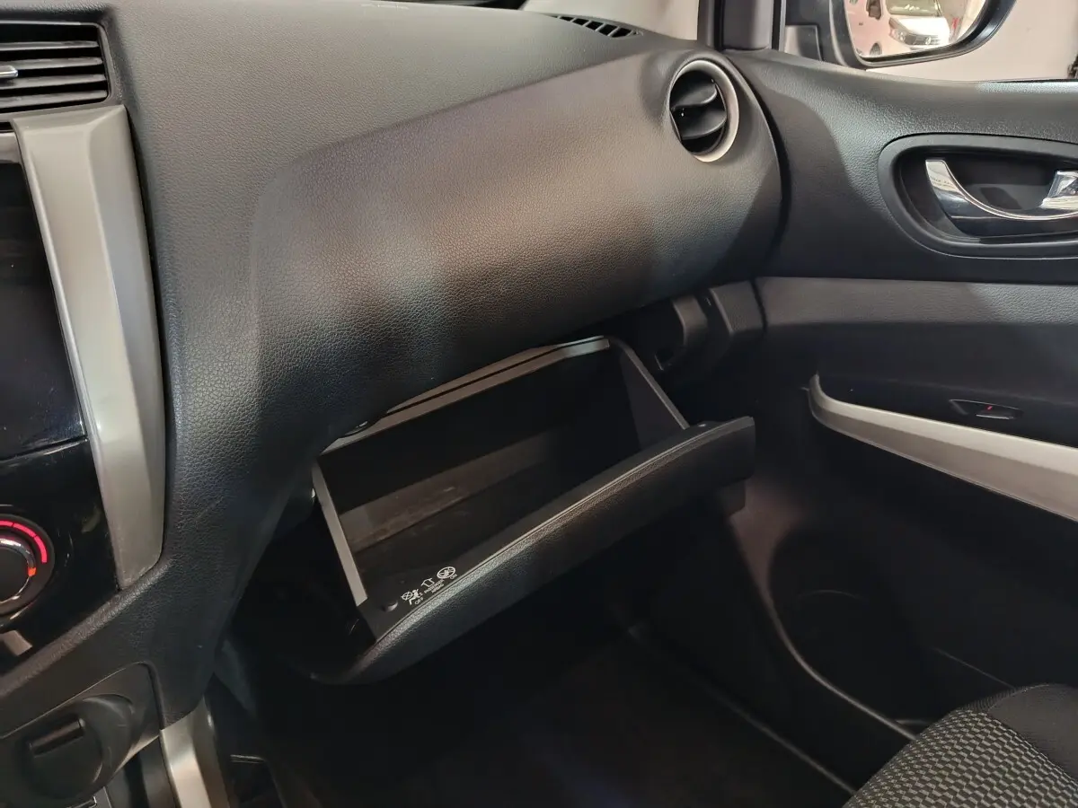 Vue intérieure du tableau de bord côté passager du Nissan Navara gris clair, avec boîte à gants ouverte et garnitures noires.