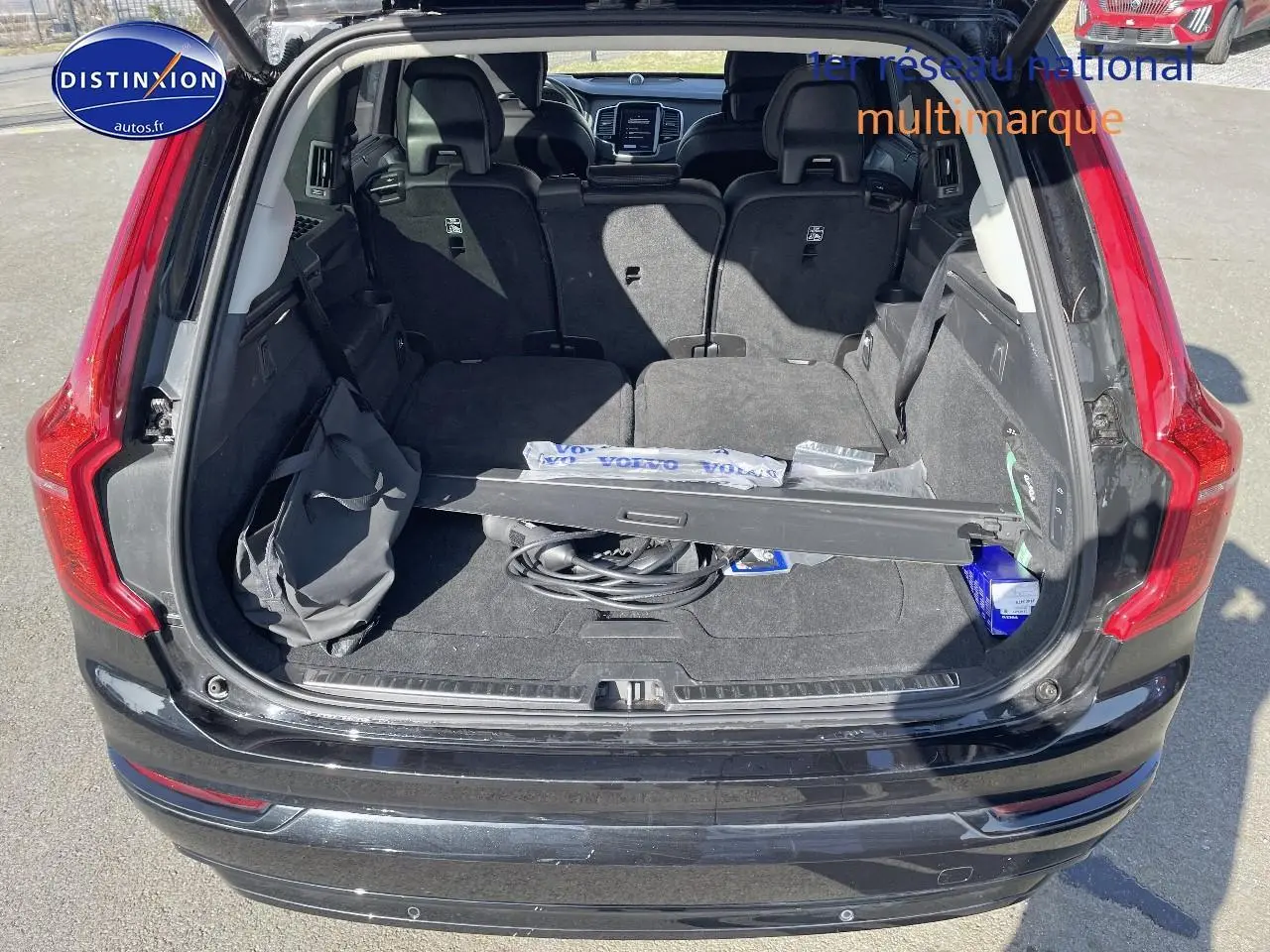 Coffre ouvert d'un Volvo XC90 noir 2023, montrant l'espace de chargement et les sièges arrière rabattus.