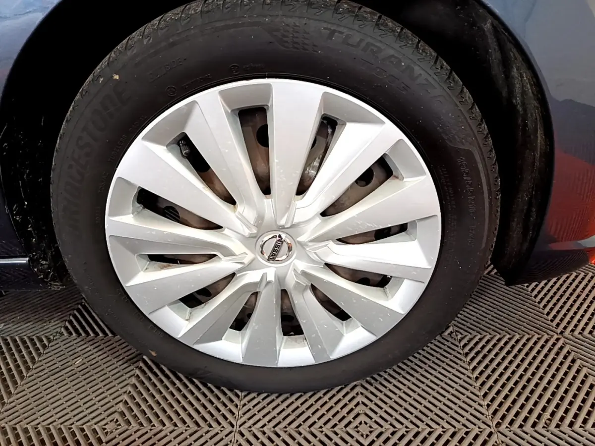 Gros plan sur la roue avant droite d’une Nissan Micra gris foncé avec enjoliveur argenté et logo central Nissan.