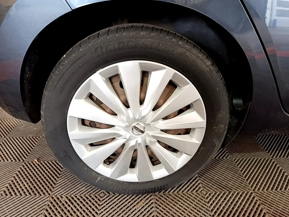 Gros plan sur la roue avant droite d’une Nissan Micra gris foncé avec jante argentée en étoile.