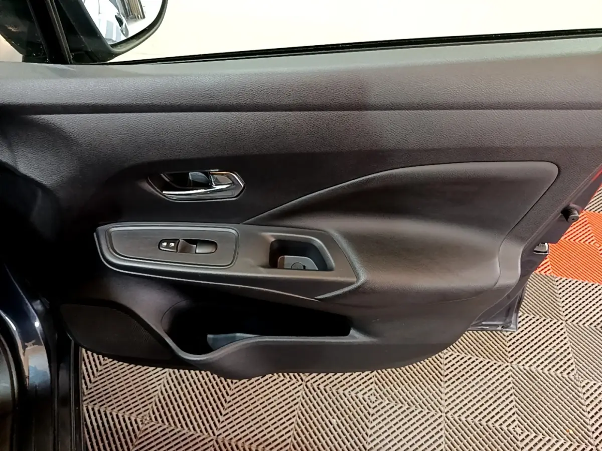 Vue rapprochée de la porte avant gauche gris foncé de la Nissan Micra 2020 avec commandes de vitres et poignée chromée.