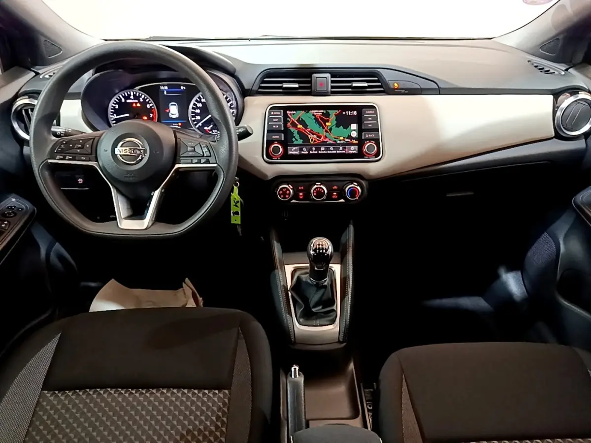 Vue intérieure frontale du tableau de bord et volant noir de la Nissan Micra IG-T 100 Business Edition avec écran tactile et levier de vitesses manuel.