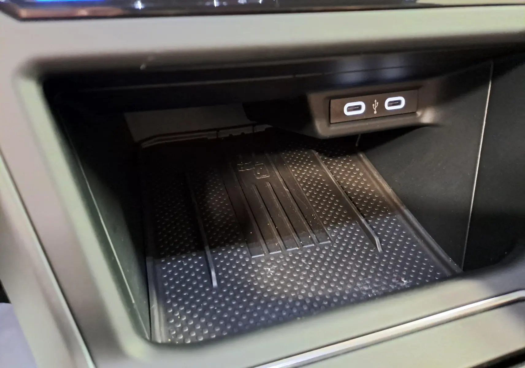 Gros plan sur la zone de recharge sans fil et ports USB-C dans l'habitacle noir du Volkswagen Taigo 2025.