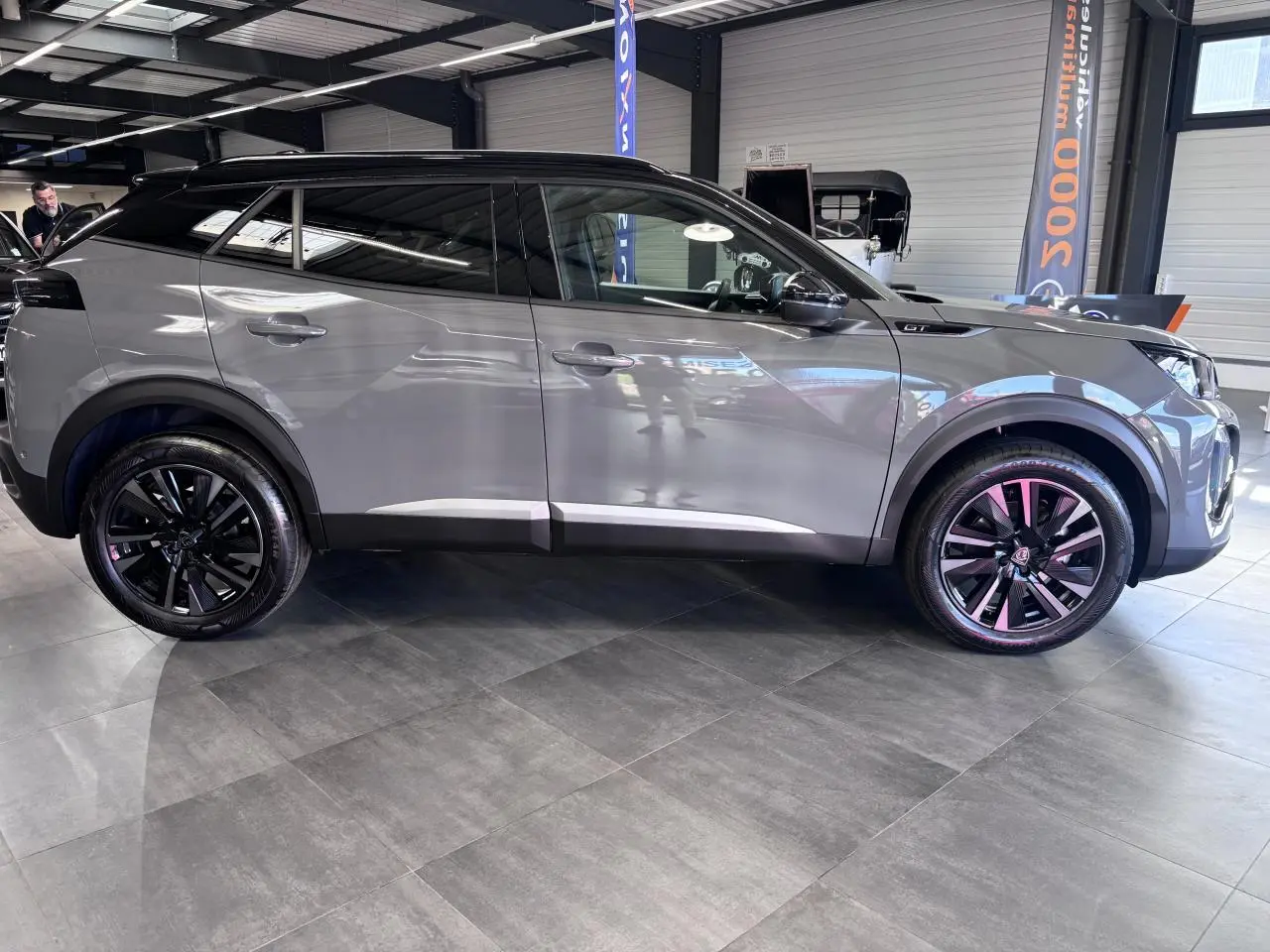 Peugeot 2008 1.2i Hybrid gris selenium vue profil droit, jantes alliage bi-ton noir et toit noir brillant.