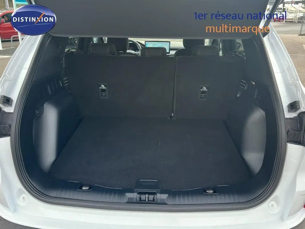 Coffre ouvert vu de l'arrière d'un Ford Kuga blanc 2025, avec banquette arrière noire et espace de chargement vide.