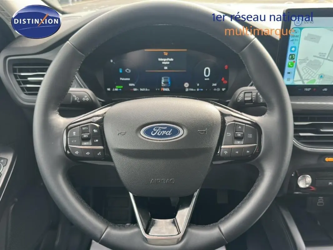 Vue rapprochée du volant noir de la Ford Kuga 2025 avec tableau de bord numérique et écran tactile latéral.