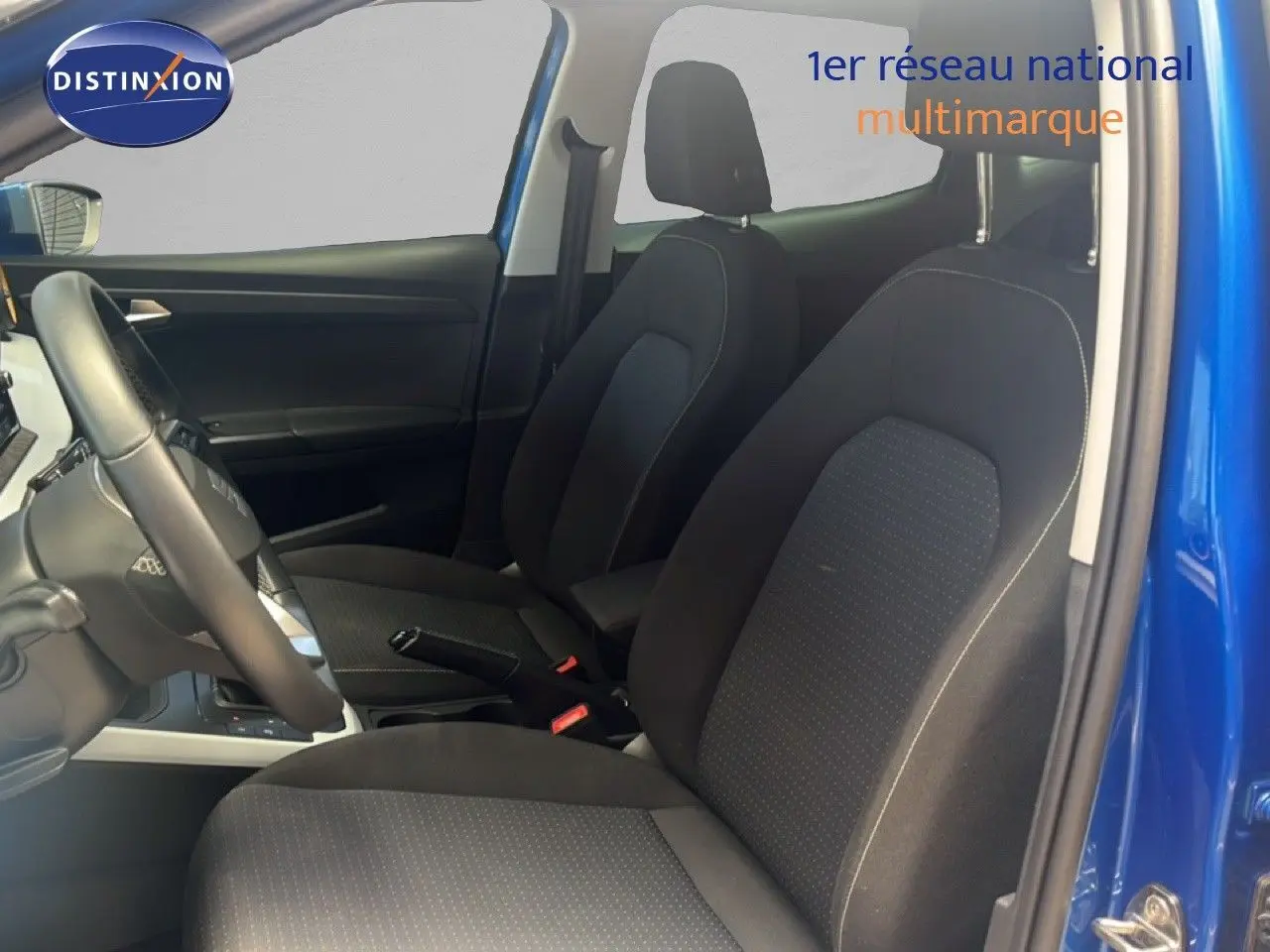 Vue intérieure côté conducteur du SEAT Arona bleu saphir, montrant les sièges avant en tissu noir et le volant cuir.