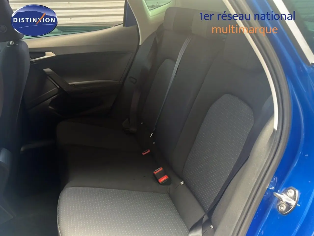 Vue intérieure arrière côté droit du SEAT Arona bleu saphir avec sièges tissu noirs et ceintures visibles.
