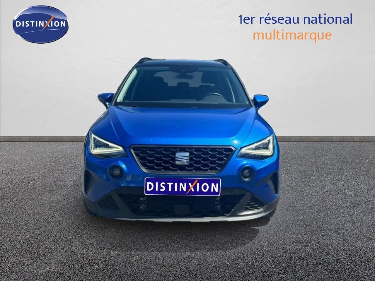 Vue avant d'un SEAT Arona bleu saphir métal avec toit noir, mettant en valeur ses phares LED et sa calandre distinctive.
