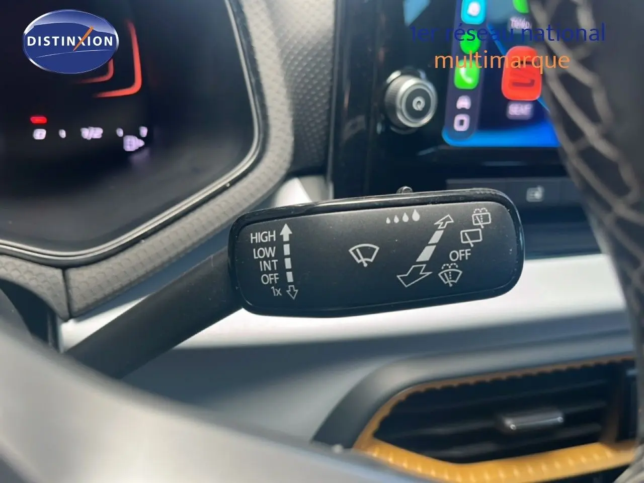 Gros plan sur la commande d’essuie-glace du SEAT Arona 2025, avec tableau de bord et écran tactile en arrière-plan.