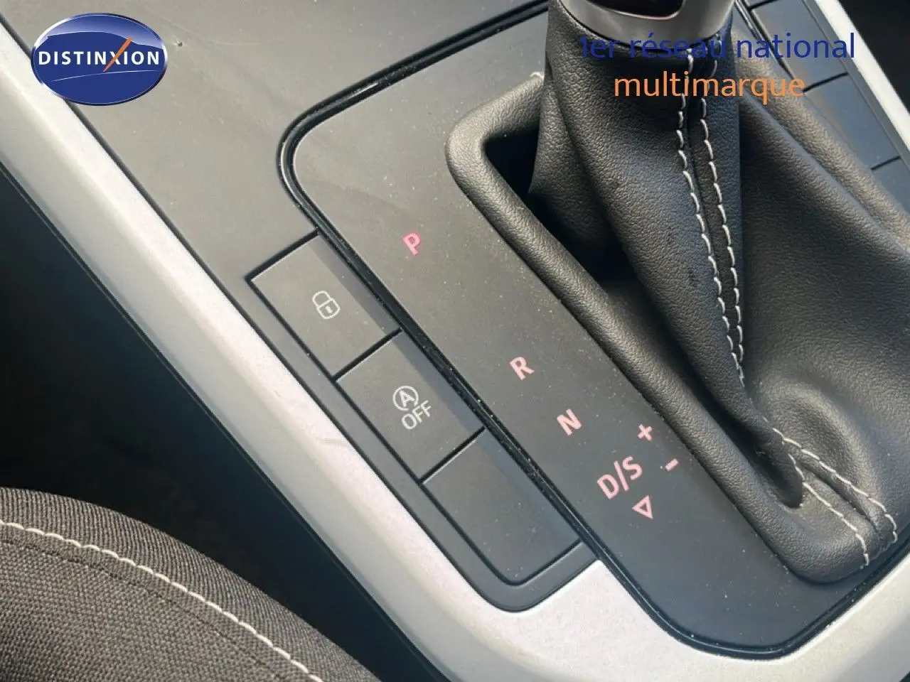 Gros plan sur la console centrale et levier de vitesses automatique du SEAT Arona bleu saphir avec surpiqûres blanches.