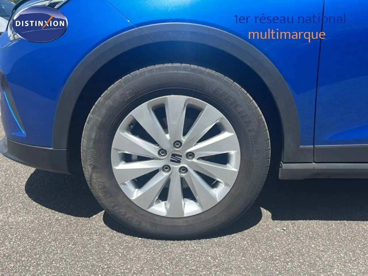 Gros plan sur la roue avant gauche d'une SEAT Arona bleu saphir avec jante argentée et passage de roue noir.