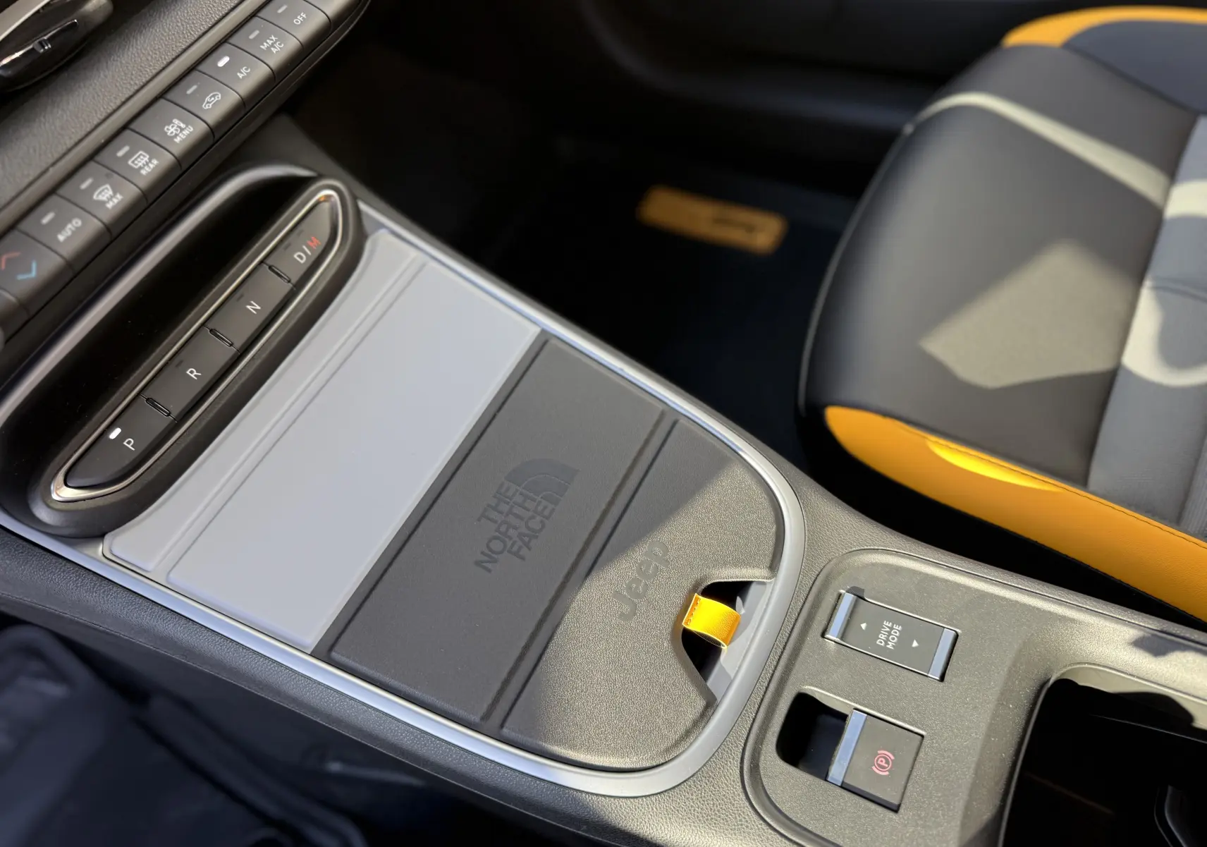 Vue rapprochée de la console centrale du Jeep Avenger 2025, avec logo The North Face et sellerie noire et orange.