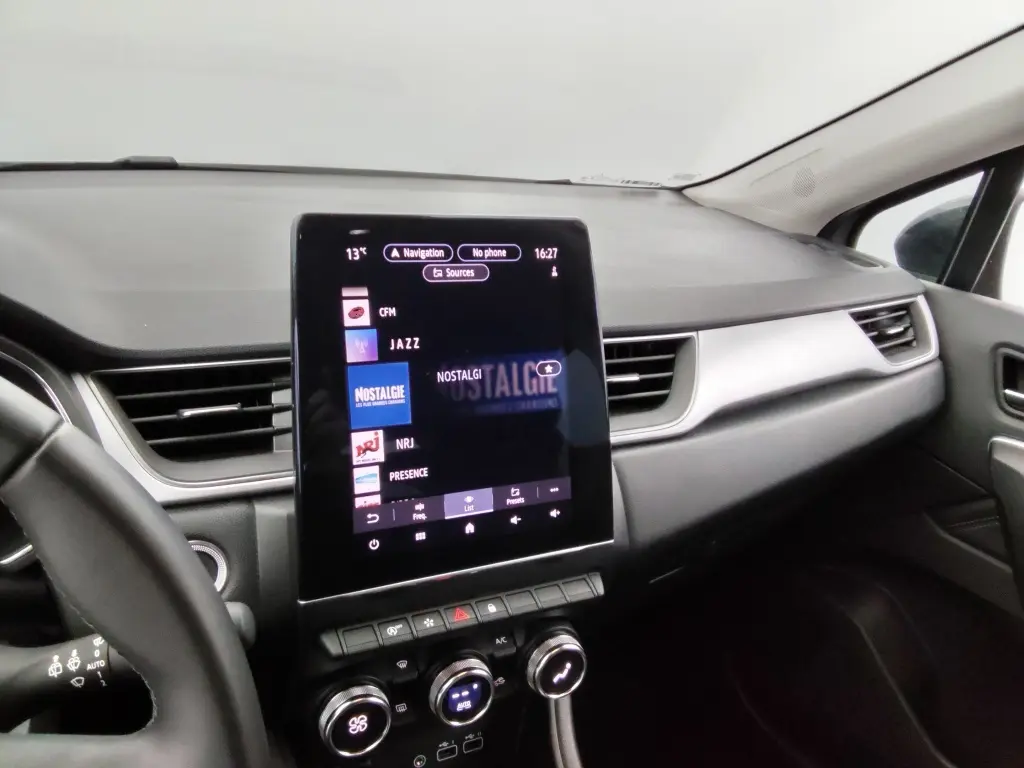 Vue intérieure côté passager du tableau de bord du Renault Captur 2024, avec écran tactile central et commandes climatisation.