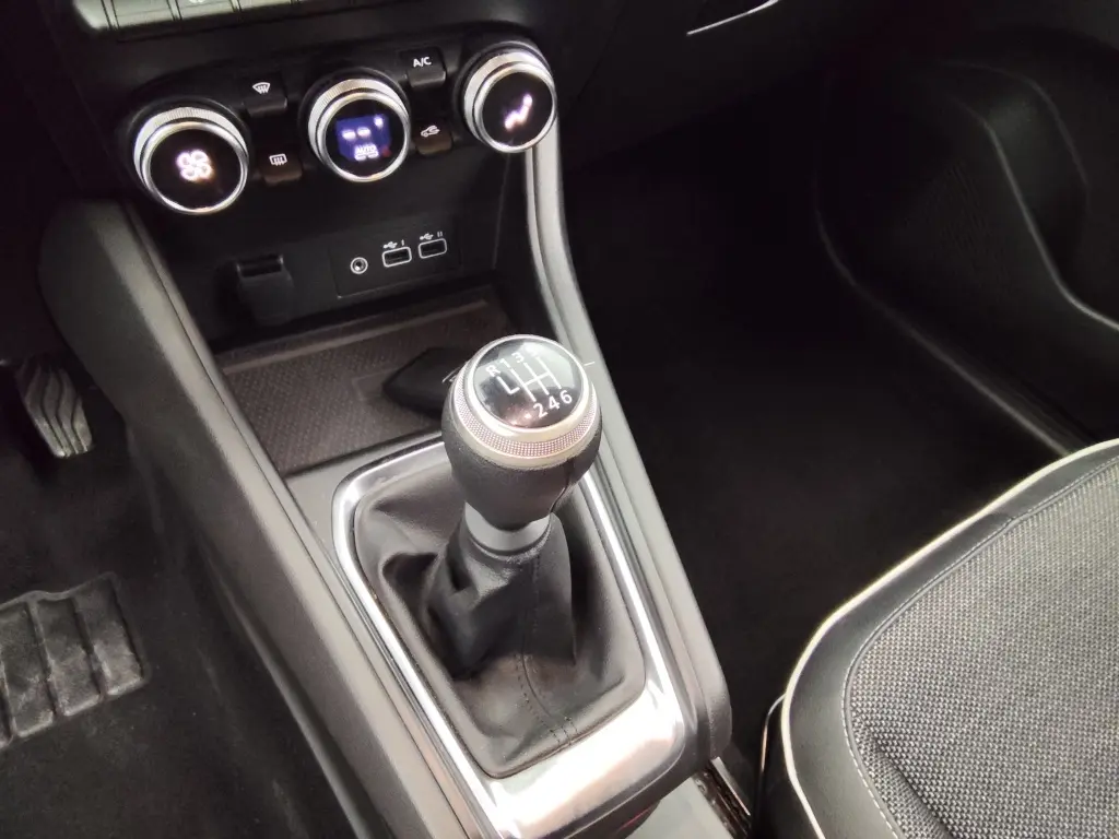 Gros plan sur la console centrale du Renault Captur 2024 gris cassiope, mettant en valeur le levier de vitesse manuel et les commandes de climatisation.