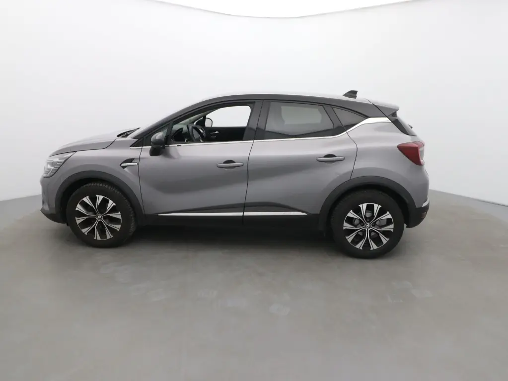 Vue de profil côté gauche du Renault Captur 2024 gris cassiope avec toit noir et jantes alliage bicolores.
