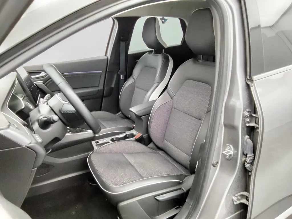 Vue intérieure côté conducteur de la Renault Captur 2024 gris cassiope avec sièges tissu et cuir noir, volant multifonction.