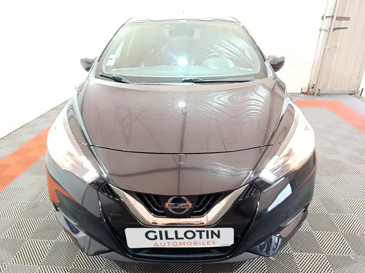 Vue avant d'une Nissan Micra IG-T 90 N-Connecta noire, avec phares allumés et calandre chromée visible.