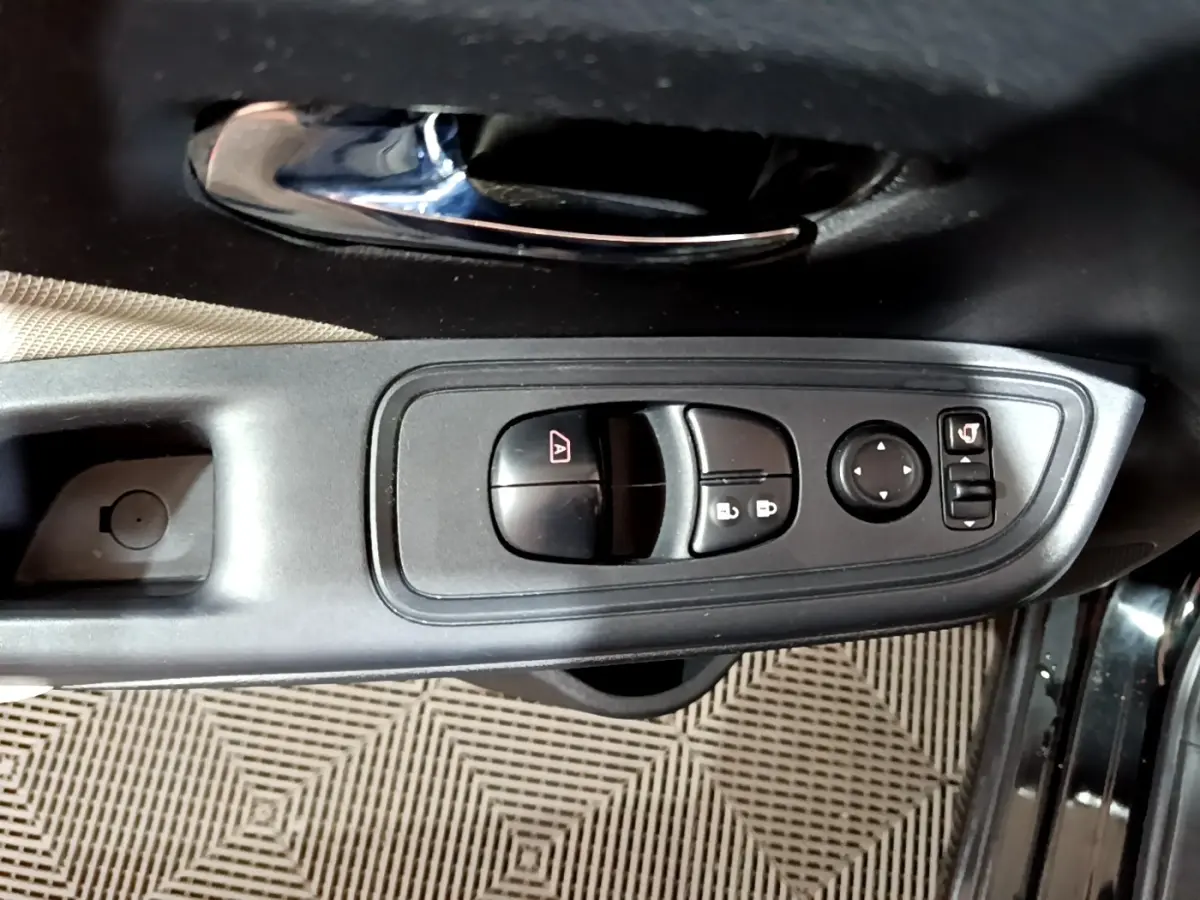 Vue rapprochée de la commande des vitres et rétroviseurs sur la porte côté gauche d'une Nissan Micra noire.
