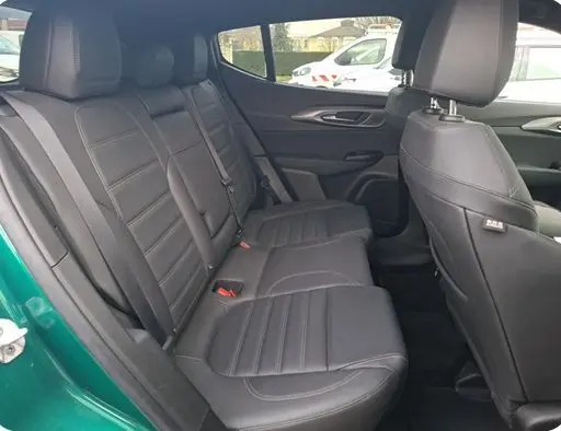 Vue latérale intérieure du siège arrière en cuir noir de l'Alfa Romeo Tonale vert foncé, montrant l'espace passagers et les ceintures.