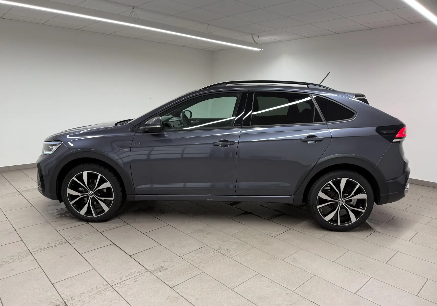 Vue de profil côté gauche du Volkswagen Taigo gris cendre avec jantes alliage 18 pouces en intérieur neutre.