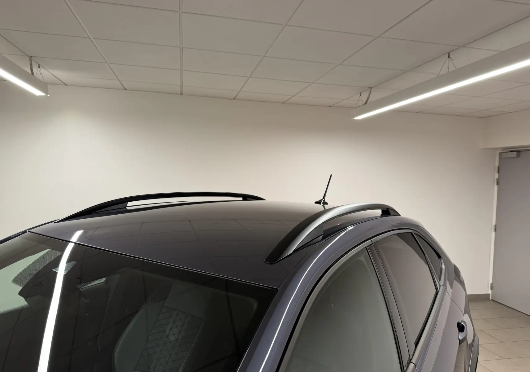 Vue partielle en plongée du toit noir brillant et des barres de toit gris cendre du Volkswagen Taigo 1.0 TSI R-Line Edition.