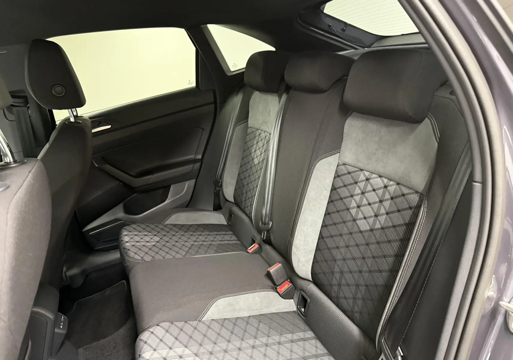 Vue intérieure côté droit de la banquette arrière du Volkswagen Taigo gris cendre avec sièges bi-matière et motifs géométriques.