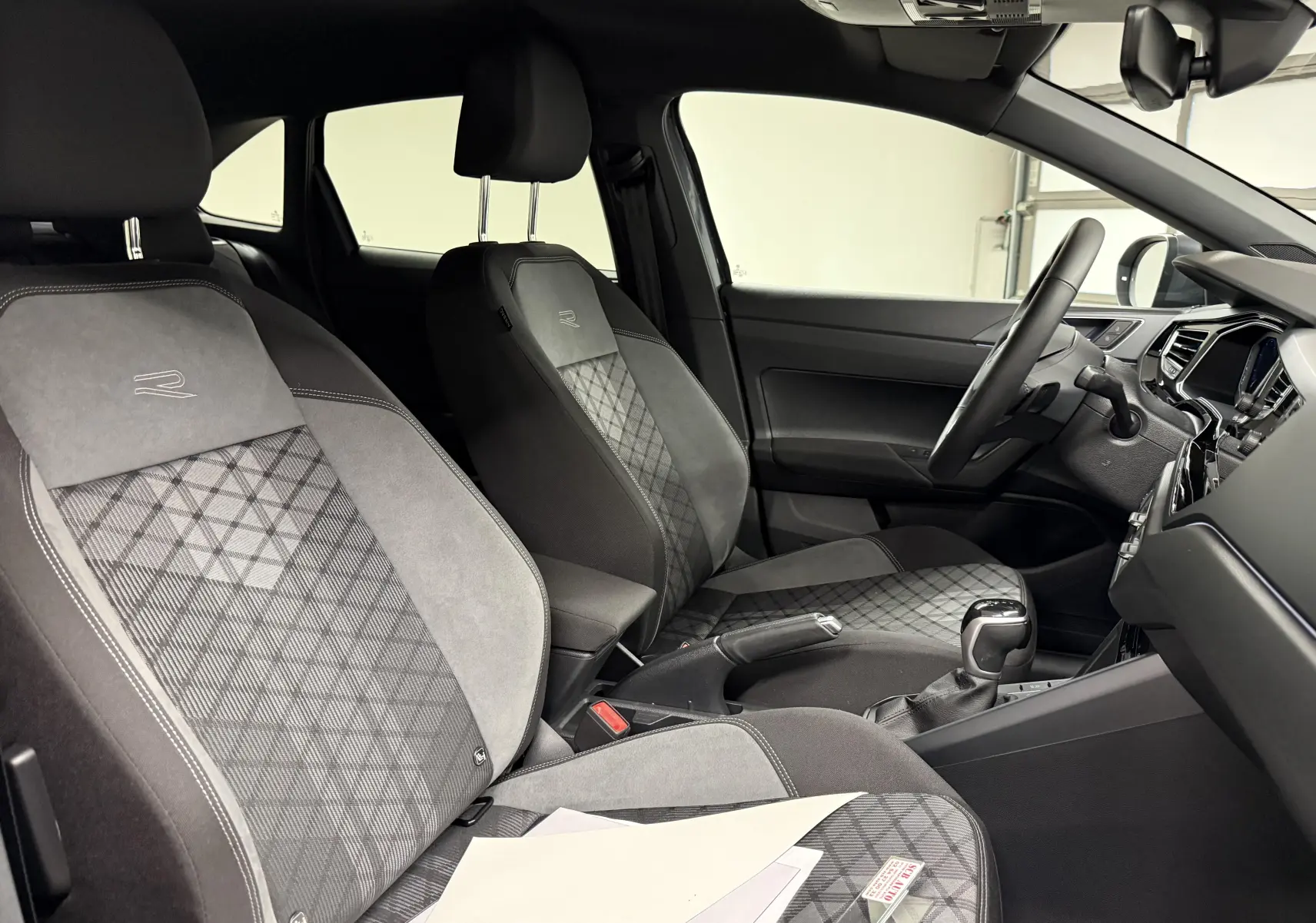 Vue intérieure côté conducteur du Volkswagen Taigo R-Line avec sièges sport gris à motifs géométriques et volant multifonctions.